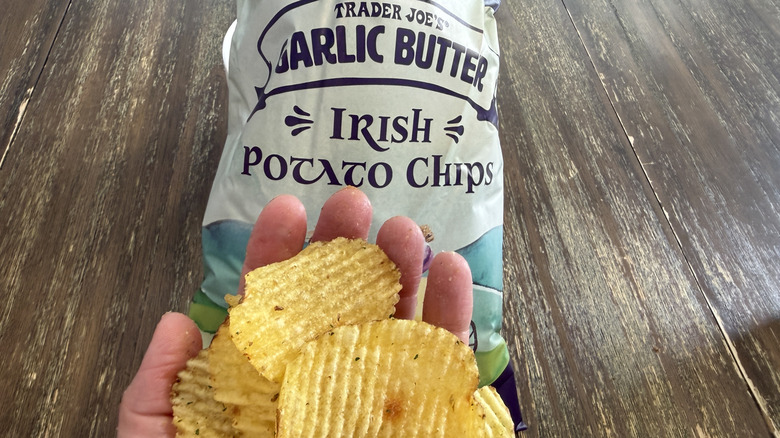 Trader Joe's Garlic Butter Irish Potato Chips on wooden table and a handful of them