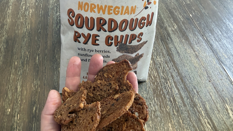 Trader Joe's Norwegian Sourdough Rye Chips on wooden table and a handful of them