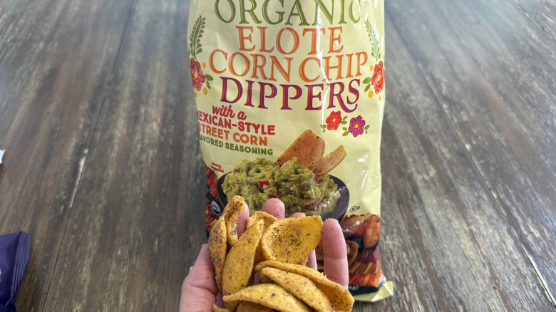 Trader Joe's Elote Corn Chips on wooden table and a handful of them