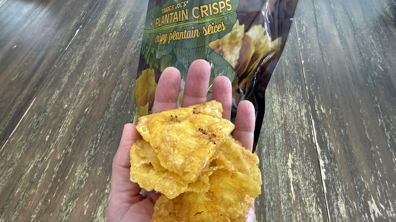 Trader Joe's Plantain Crisps on wooden table and a handful of them
