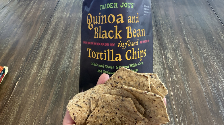 Trader Joe's Quinoa and Black Bean Tortilla Chips on wooden table and a handful of them