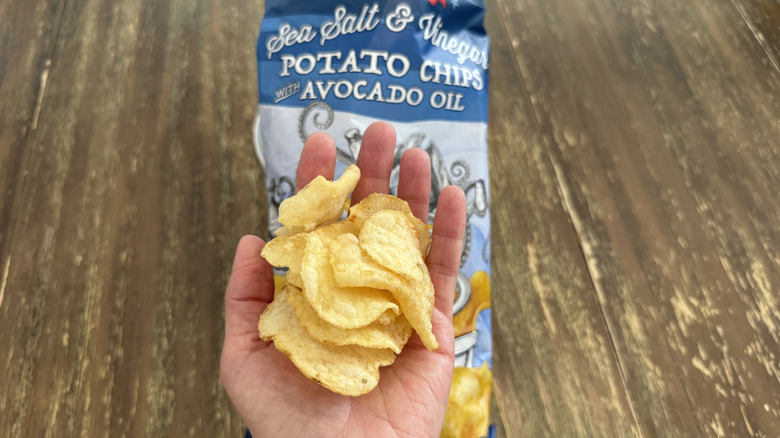Trader Joe's Sea Salt & Vinegar Chips on wooden table and a handful of them
