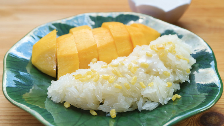 Sliced mango and sticky rice on a green plate