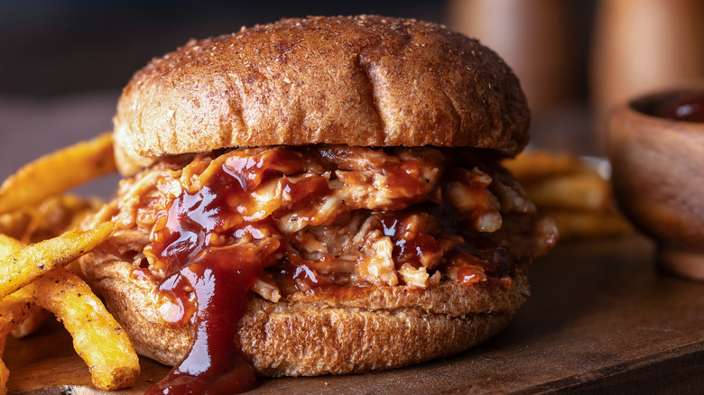 pulled pork on sandwich on wheat bun with fries
