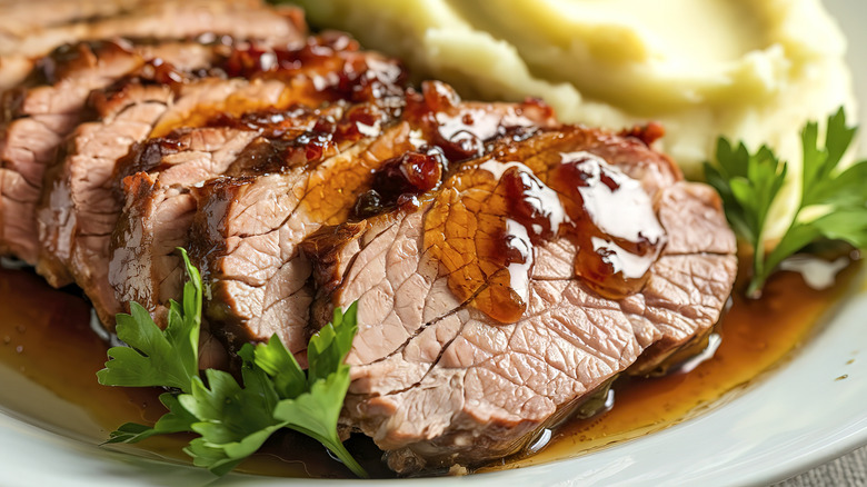 sliced beef topped with glaze on white plate