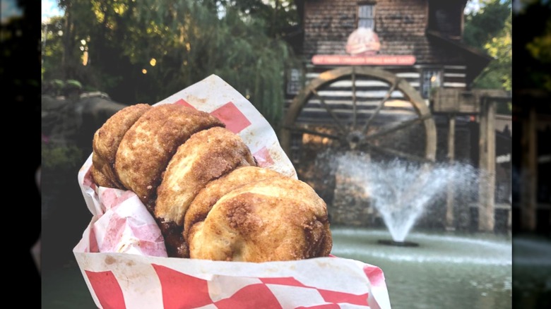 A basket of cinnamon bread with an old mill in the background