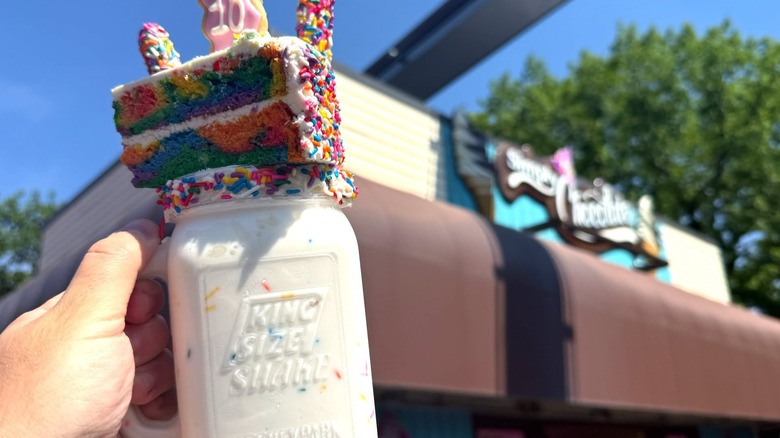 Someone holding a cake-topped shake next to the Simply Chocolate store in Hersheypark