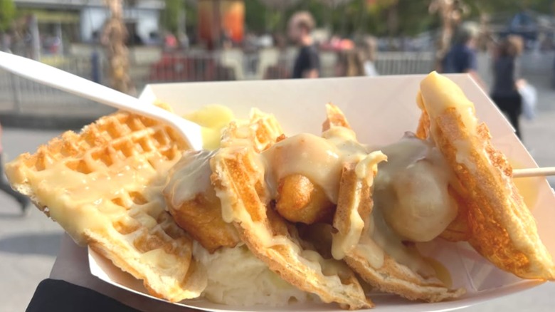 Gravy-covered chicken and waffles in a white container