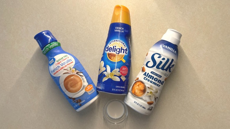 bottles of storebought vanilla creamer on counter with small glass of creamer
