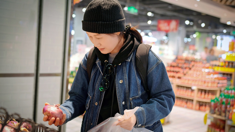woman inspecting an onion at the grocery store