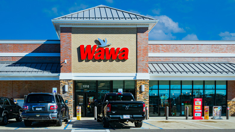 Exterior of a Wawa convenience store entrance with cars in parking lot during day