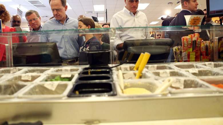 People ordering from a Wawa kiosk with condiments in the foreground