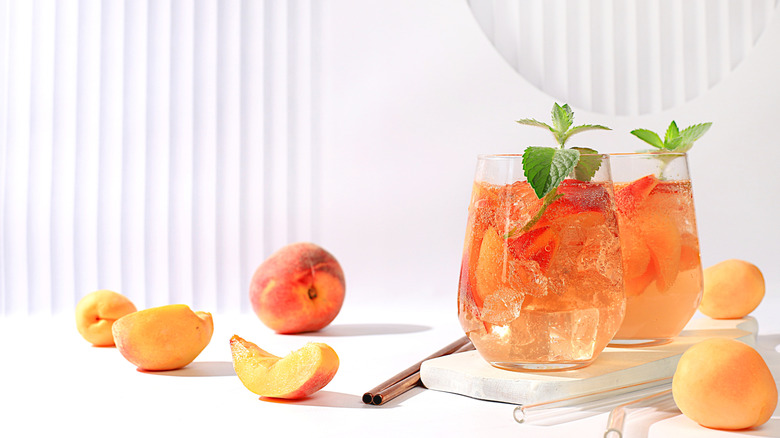 Glasses of lemonade with peaches on a white background