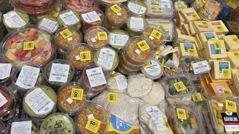 Plastic containers of fresh cut fruit, salsas, and cheeses with yellow half off stickers