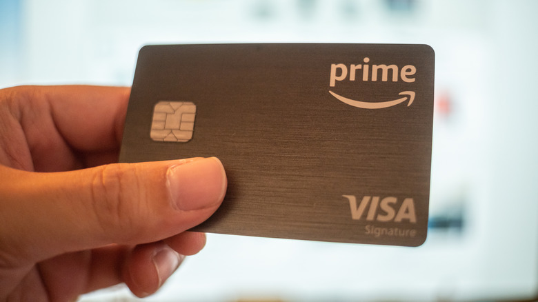 Close up of a hand holding a gray prime Visa credit card