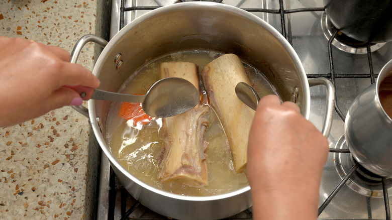 A person making homemade bone broth on a stove