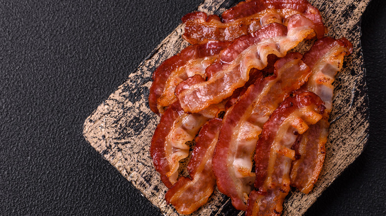 Cooked bacon slices on a wood board