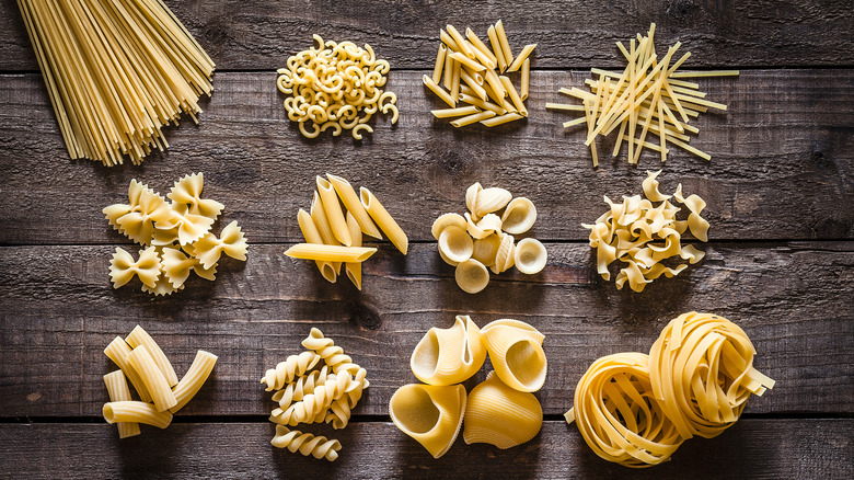 Different types of uncooked pasta on a wood table