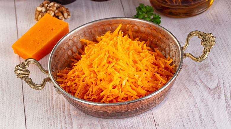 Shredded yellow cheese in a silver bowl