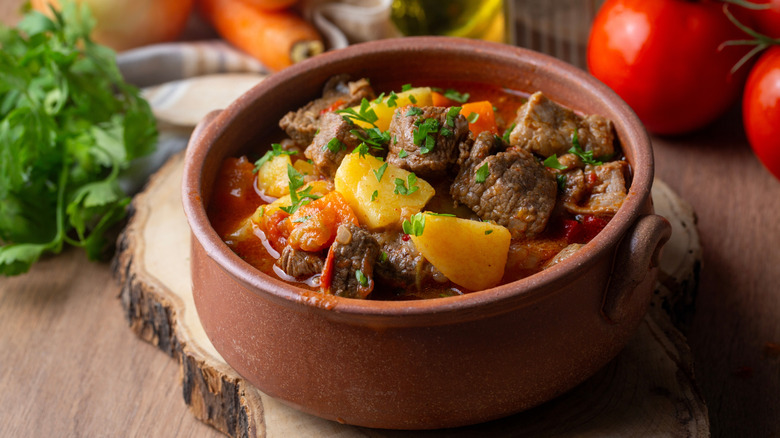 Goulash in a brown bowl on a wood board