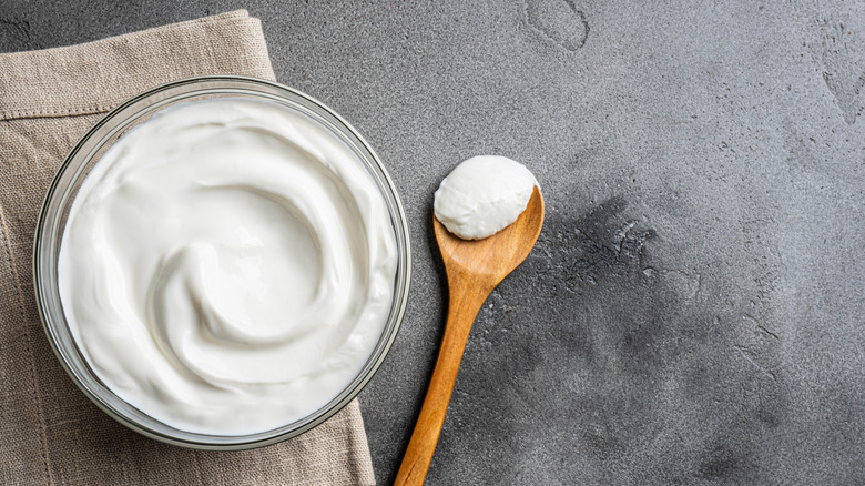 A bowl of sour cream with a wood spoon