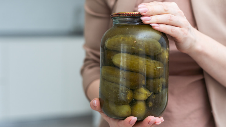 Hands holding jar of pickles