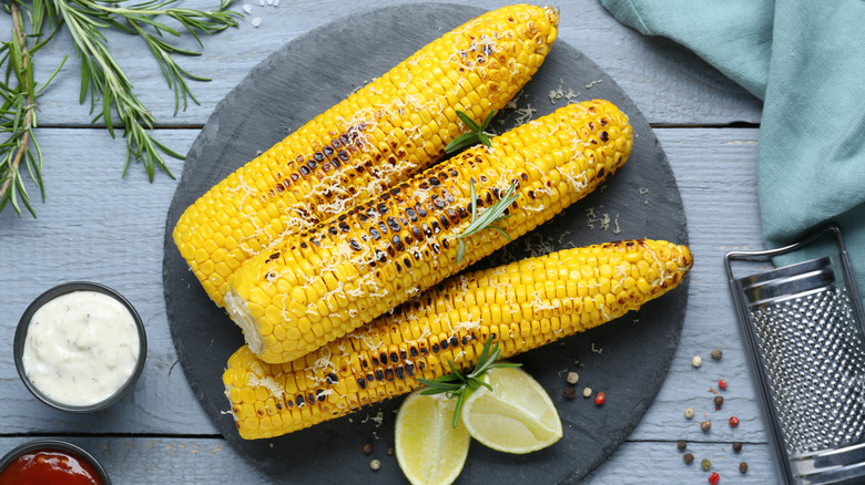 charred corn on a plate with seasonings arranged around