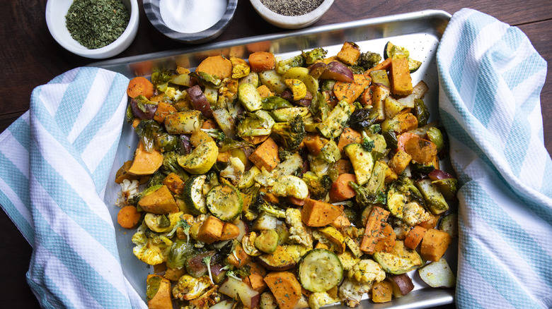 A sheet pan of roasted vegetables set on a wood background
