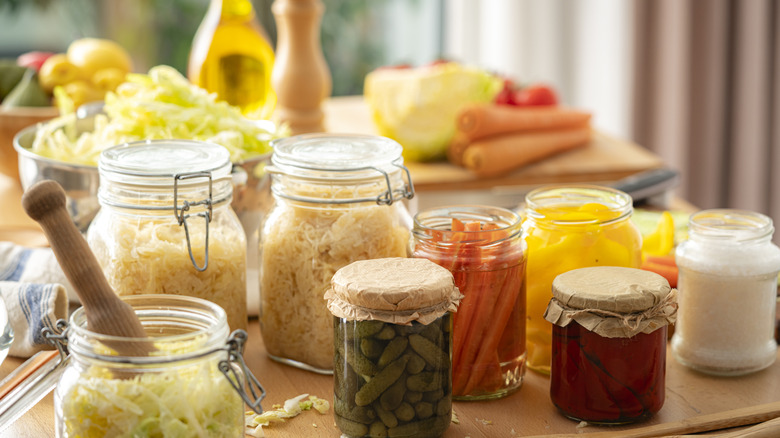 Various fermented and pickled vegetables in glass jars on kitchen table