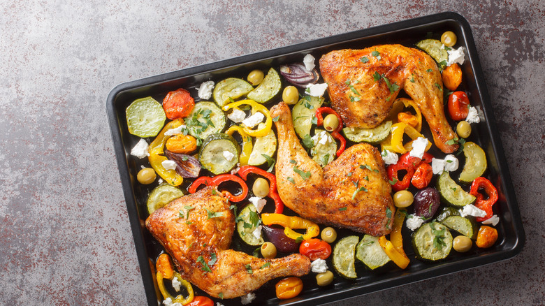 A baking sheet filled with roasted chicken thighs and vegetables