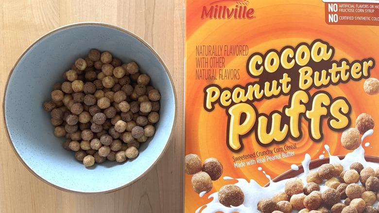 A bowl of cereal next to a box of Cocoa Peanut Butter Puffs