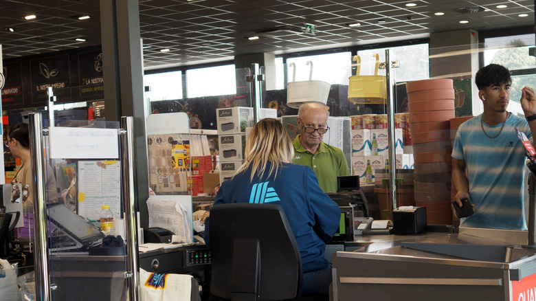 An Aldi cashier photographed from behind as she helps customers pay for groceries
