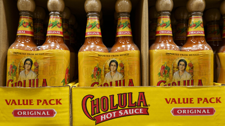 Bulk packages of bottles of Cholula hot sauce on a grocery store shelf