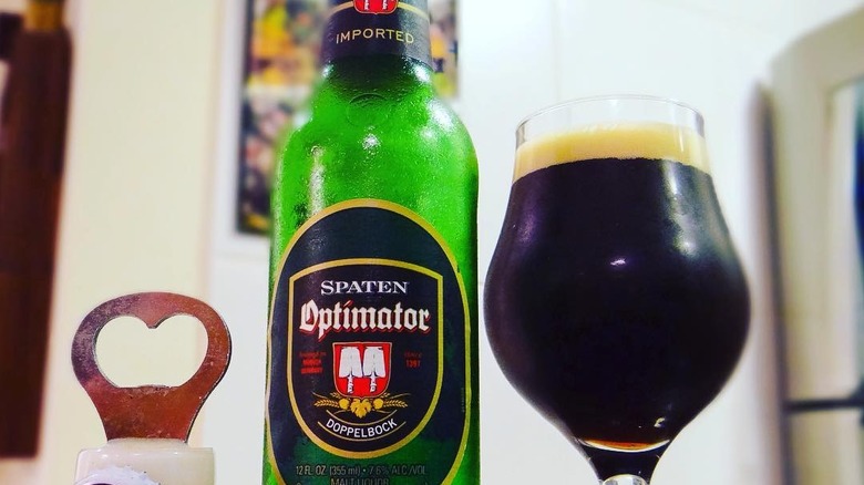 An empty bottle of Spaten Optimator next to a full tulip glass