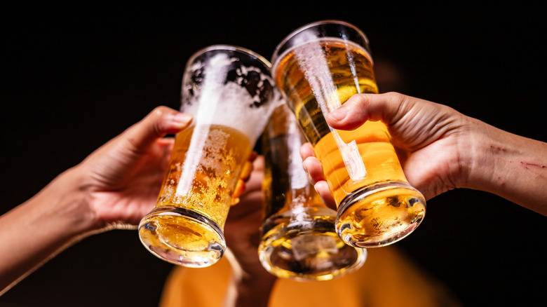 Several people clinking beer glasses in a toast