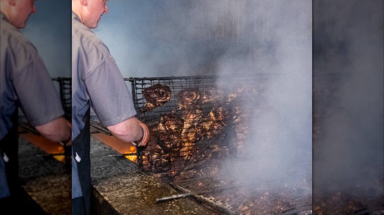 pitmaster grilling chicken at brooks house of bar-b-q over their 38 foot pit