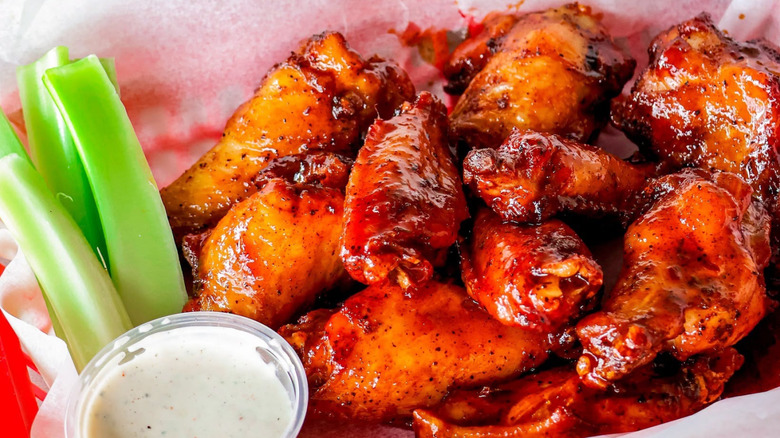 basket of saucy wings from smokey d's with a side of white sauce and celery