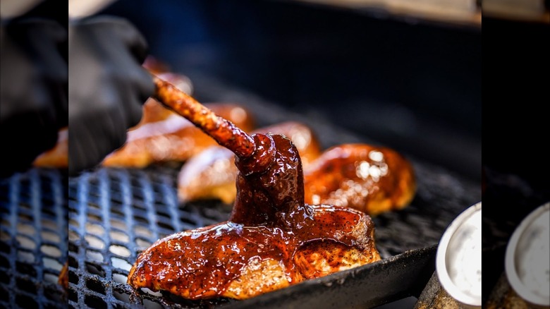 barbecue chicken from wright's being brushed with peppery bbq sauce on smoker