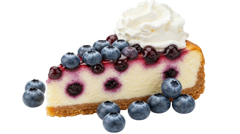 Isolated Blueberry Cheesecake Slice Topped with Whipped Cream