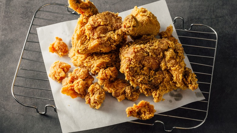 Top-down view of fried chicken resting on parchment paper atop an oven rack