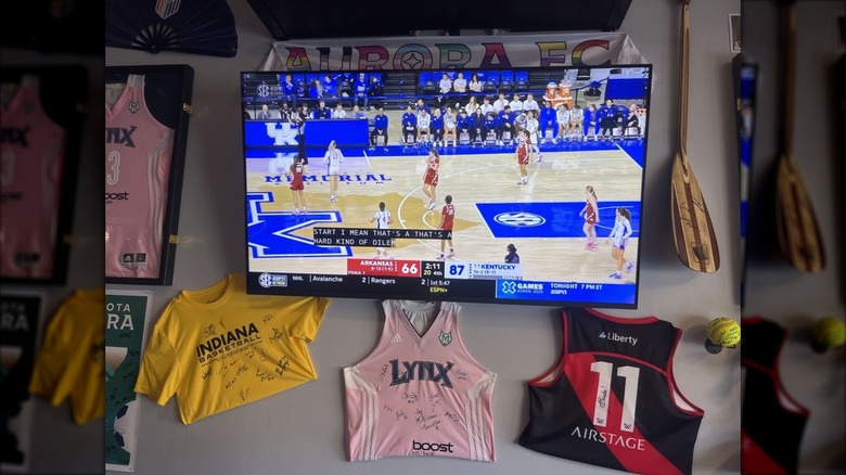 A wall at A Bar of Their Own: a TV playing women's basketball surrounded by women's team jerseys