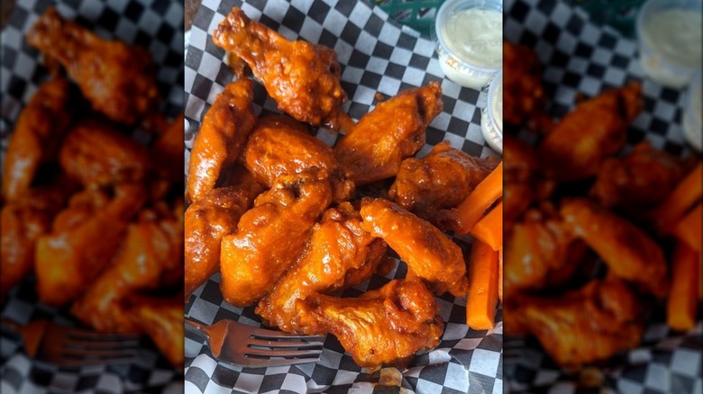 Chicken wings with carrot sticks in a black-and-white checkerboard-lined basket