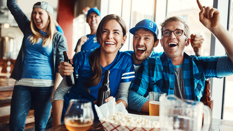 A group of sports fans in a bar, all dressed in blue and cheering