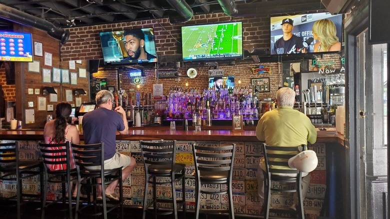 PS Tavern with three patrons sitting at the bar, sports playing on three televisions