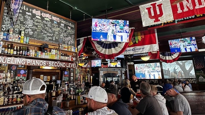 The interior of Sluggers Bar, with crowded bar and shelves of bottles and cans