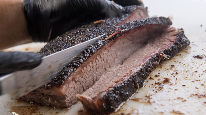 Close up of a chef slicing pieces of brisket.