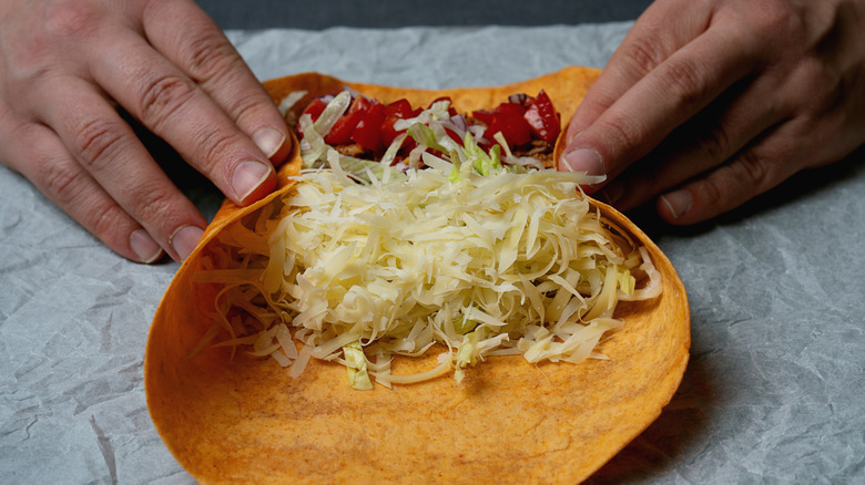 a tortilla with grated cheese being wrapped