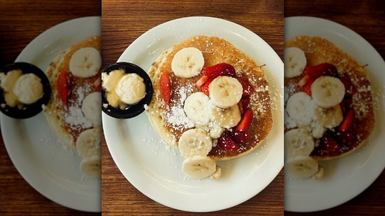 Top down view of strawberry and banana pancakes on white plate from Denny's