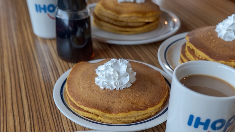 Multiple stacks of pancakes on white plates on a table at IHOP