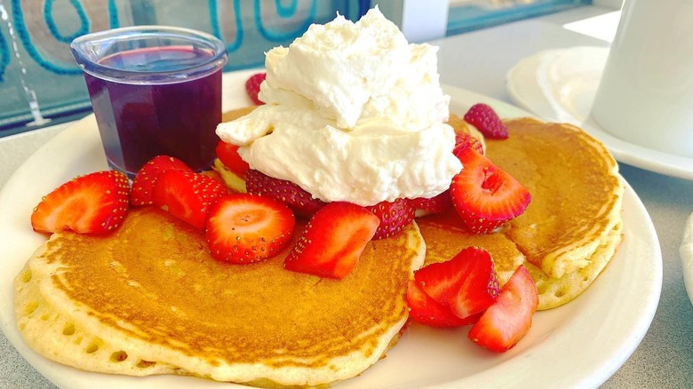 Pancakes with strawberry, whipped cream, and syrup on the side from the Original Pancake House.